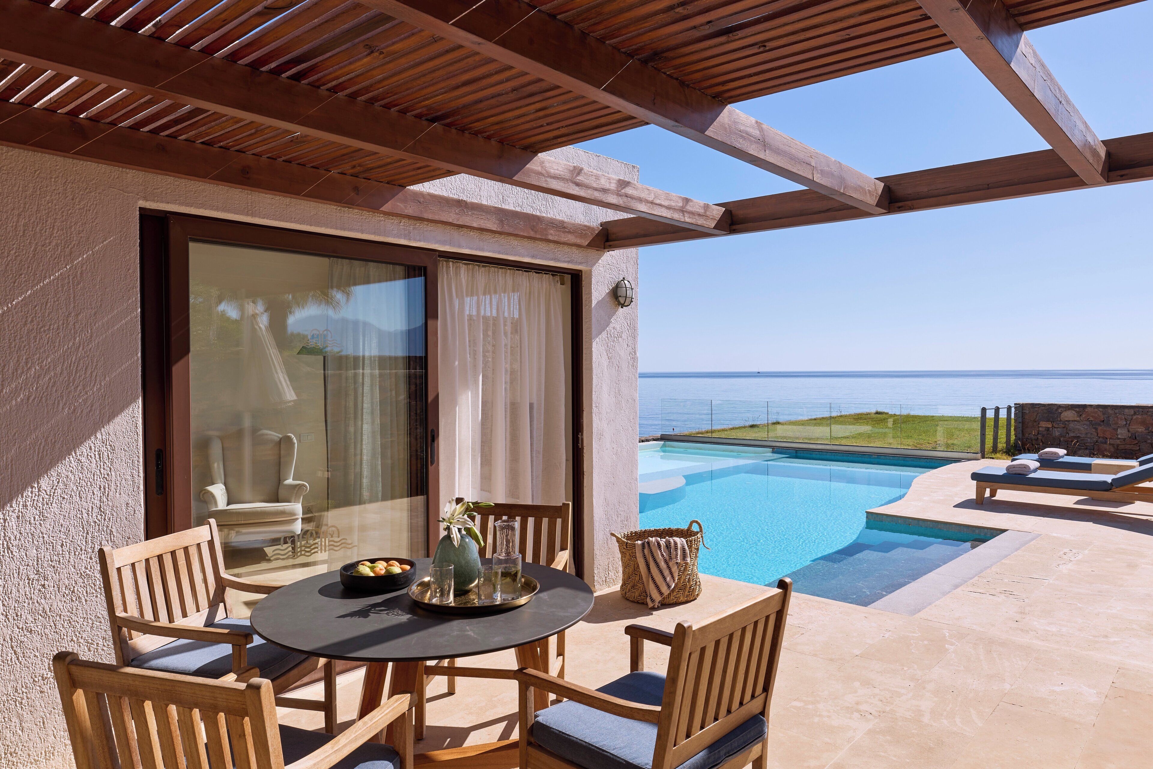 Uma área de estar coberta ao ar livre, com piscina e vista para o oceano.