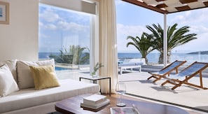 Une chambre moderne avec un canapé, une table et une vue sur la mer et les palmiers.