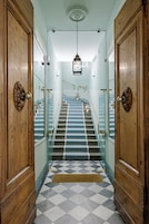 A hallway with wooden doors, a checkered floor, and a staircase with blue steps.