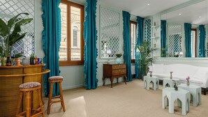 A room with a bar area, two stools, a white sofa, and a large mirror. - Room Mate Collection Isabella, Florence (Florence)