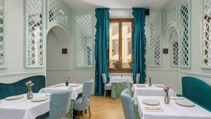 A dining area with tables set for four, each with a vase of flowers and white tablecloths. - Room Mate Collection Isabella, Florence (Florence)