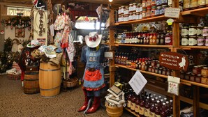 A store with shelves of various products, a mannequin dressed in a cowboy outfit, and wooden barrels on the floor. - Buffalo Bill Village Cabins (Cody)