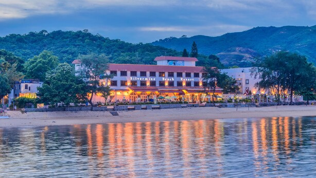 A beachfront hotel with a red roof, multiple balconies, and a swimming pool. - Silvermine Beach Resort (Mui Wo)