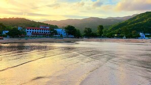 A beach with a building in the background. - Silvermine Beach Resort (Mui Wo)