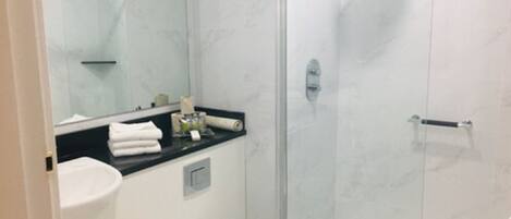 Een moderne badkamer met een glazen douchecabine, een wit toilet en een wastafel met een zwart aanrecht.