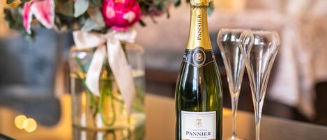 A bottle of Pannier champagne and two glasses on a reflective surface.