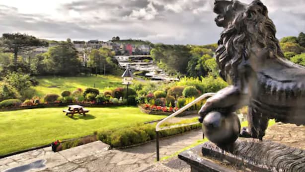 A statue of a lion in a park with a view of a building in the background. - Falls Hotel & Spa (Ennistimon)