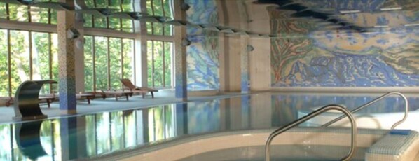 An indoor swimming pool with clear glass walls, a mural on the wall, and a few lounge chairs. - Falls Hotel & Spa (Ennistimon)