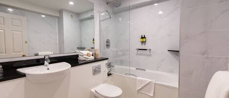 A modern bathroom with a sink, toilet, and bathtub.