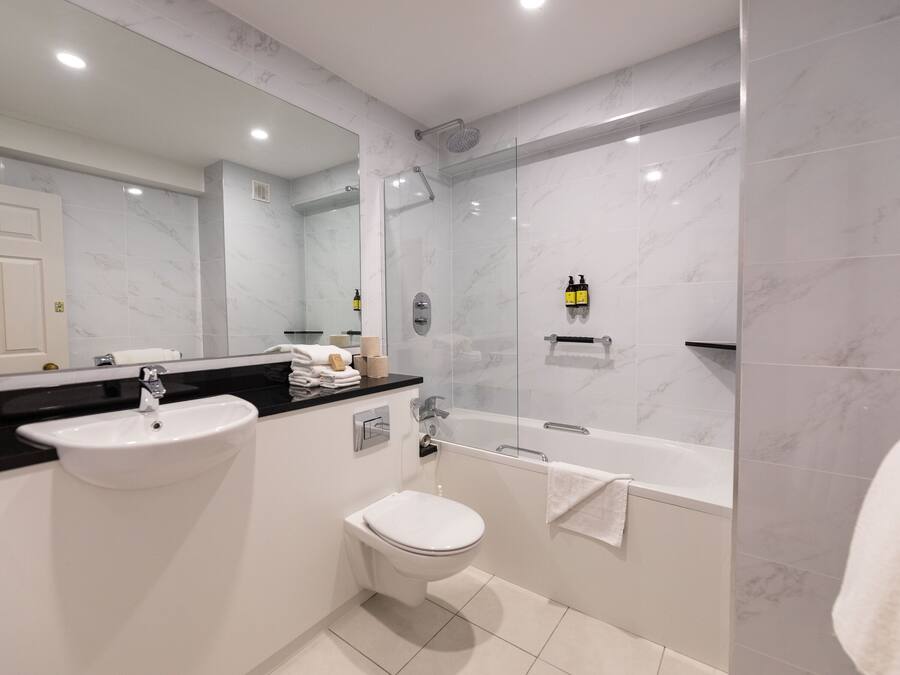 A modern bathroom with a sink, toilet, and bathtub.