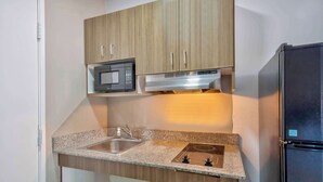 Cocina compacta con microondas, estufa, fregadero y un refrigerador negro.