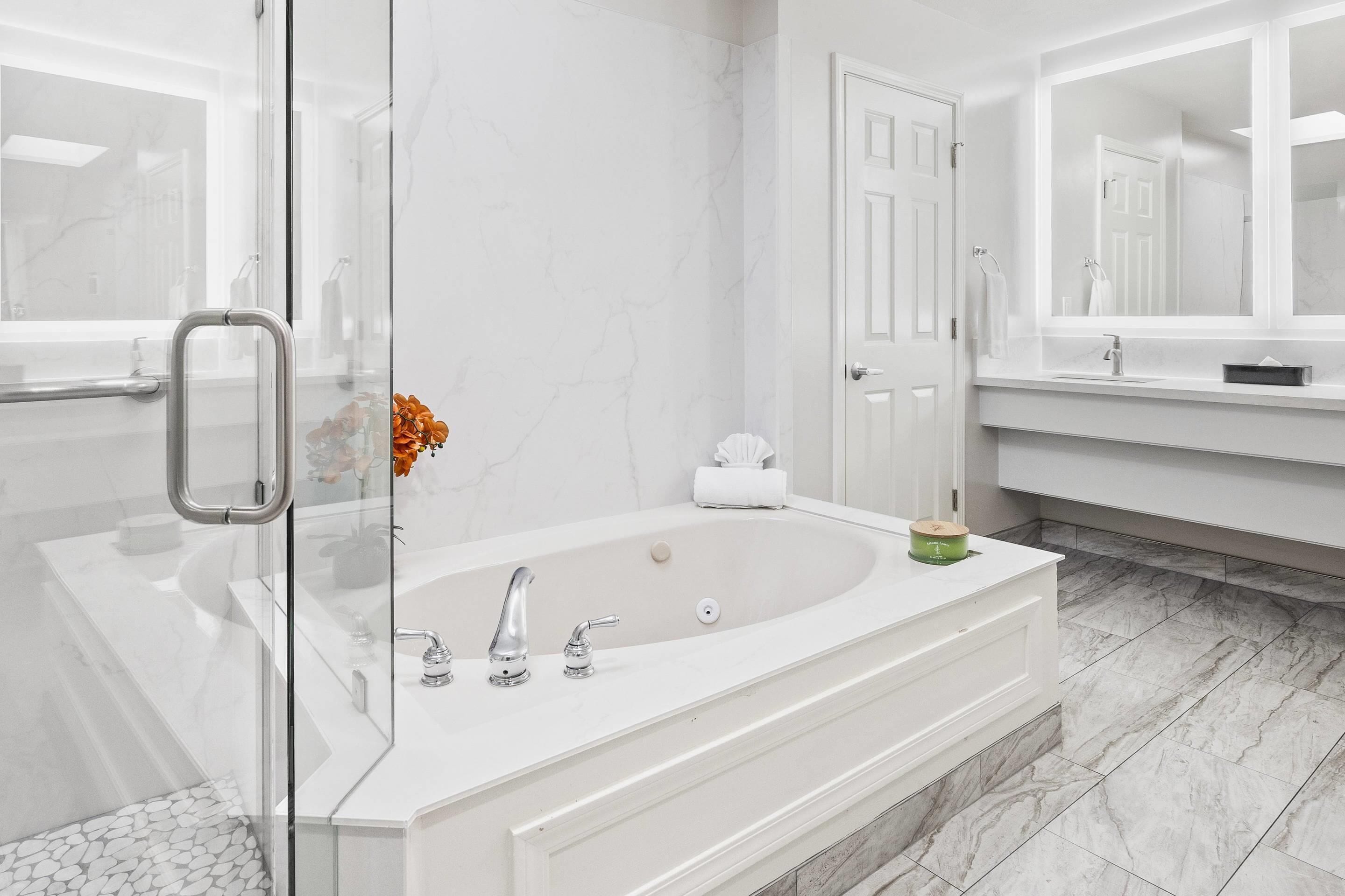 A modern bathroom with a glass shower enclosure, a freestanding bathtub, and a large mirror above the vanity.