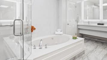 A modern bathroom with a glass shower enclosure, a freestanding bathtub, and a large mirror above the vanity.
