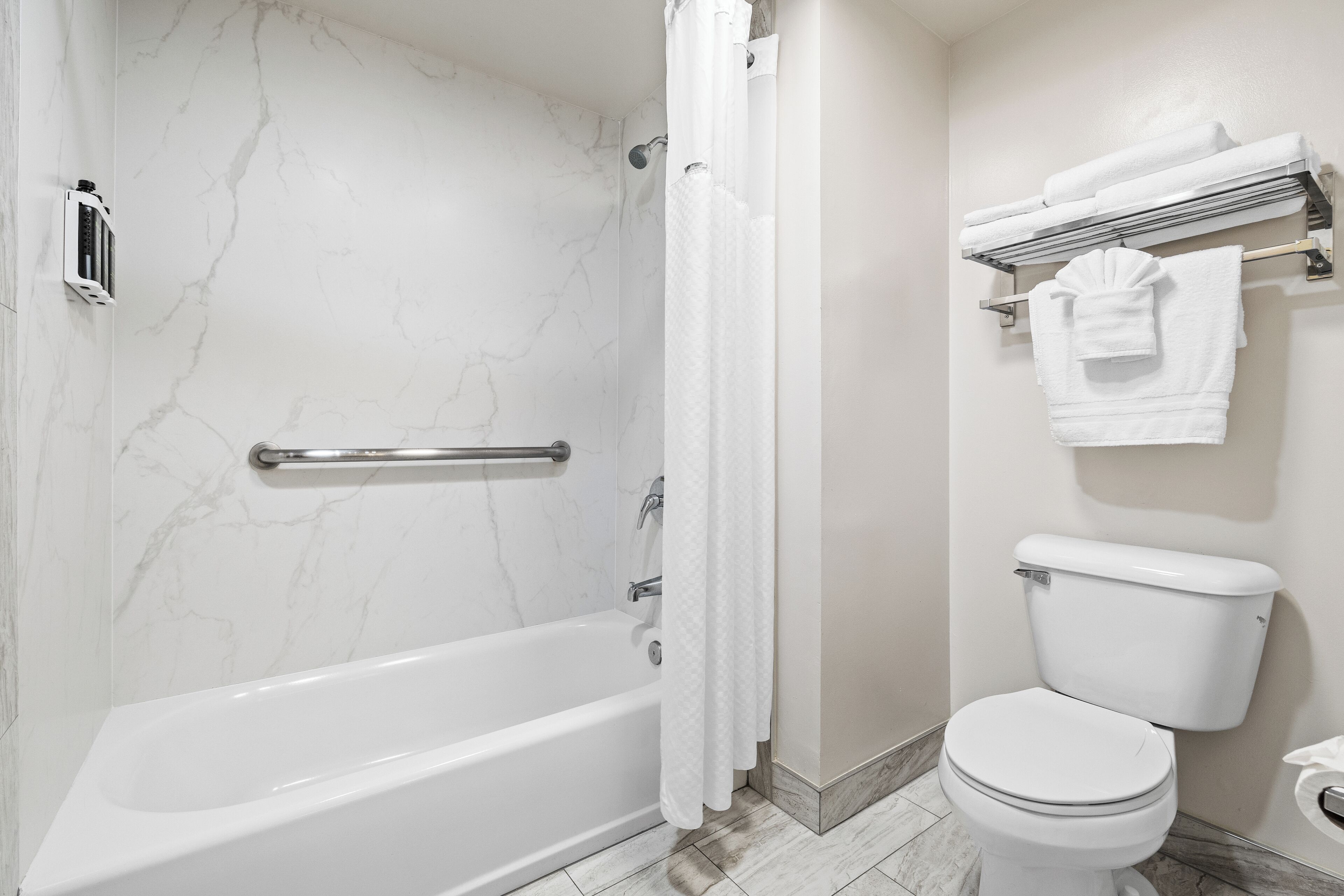 A bathroom with a bathtub, toilet, and towel rack.