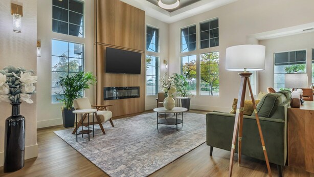 A spacious living room with a large TV, comfortable seating, a coffee table, and a floor lamp. - University Park Inn & Suites, an Ascend Collection Hotel (Davis)