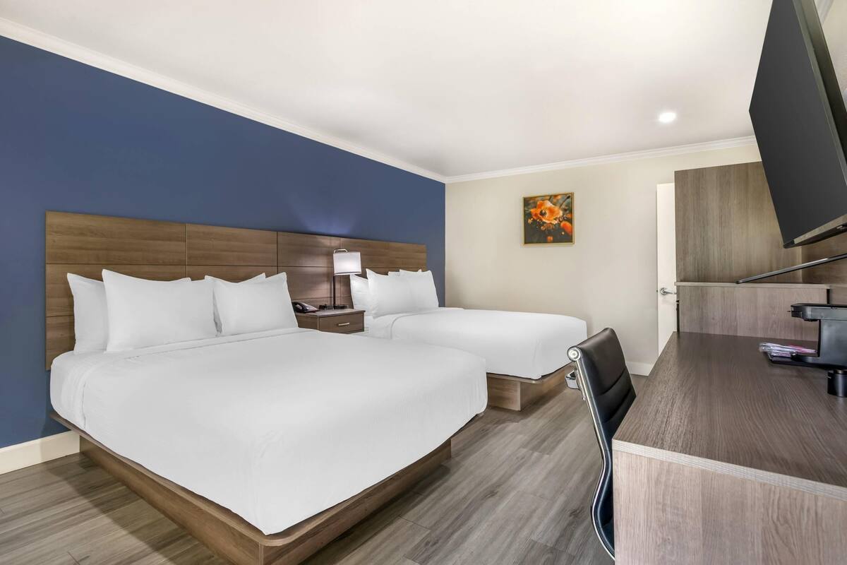 Quarto de hotel com duas camas, uma escrivaninha e uma televisão.