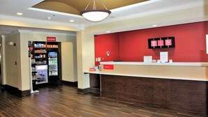 A hotel reception area with a red wall, a reception desk, and a vending machine. - TownePlace Suites by Marriott Wilmington Newark/Christiana (Newark)