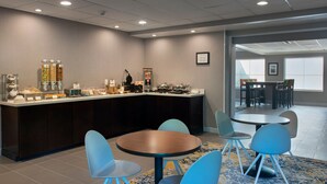 A modern hotel lobby with a breakfast bar, seating area, and large windows. - TownePlace Suites by Marriott Wilmington Newark/Christiana (Newark)