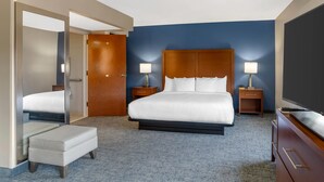 A hotel room with a large bed, two bedside tables with lamps, a wooden headboard, a flat-screen TV, and a small seating area. - Comfort Suites near Birkdale Village- Huntersville (Huntersville)