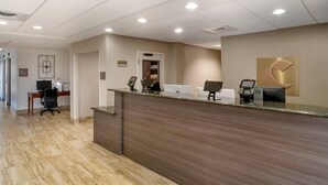 A reception area with a wooden reception desk, computers, and a phone. - Comfort Suites near Birkdale Village- Huntersville (Huntersville)