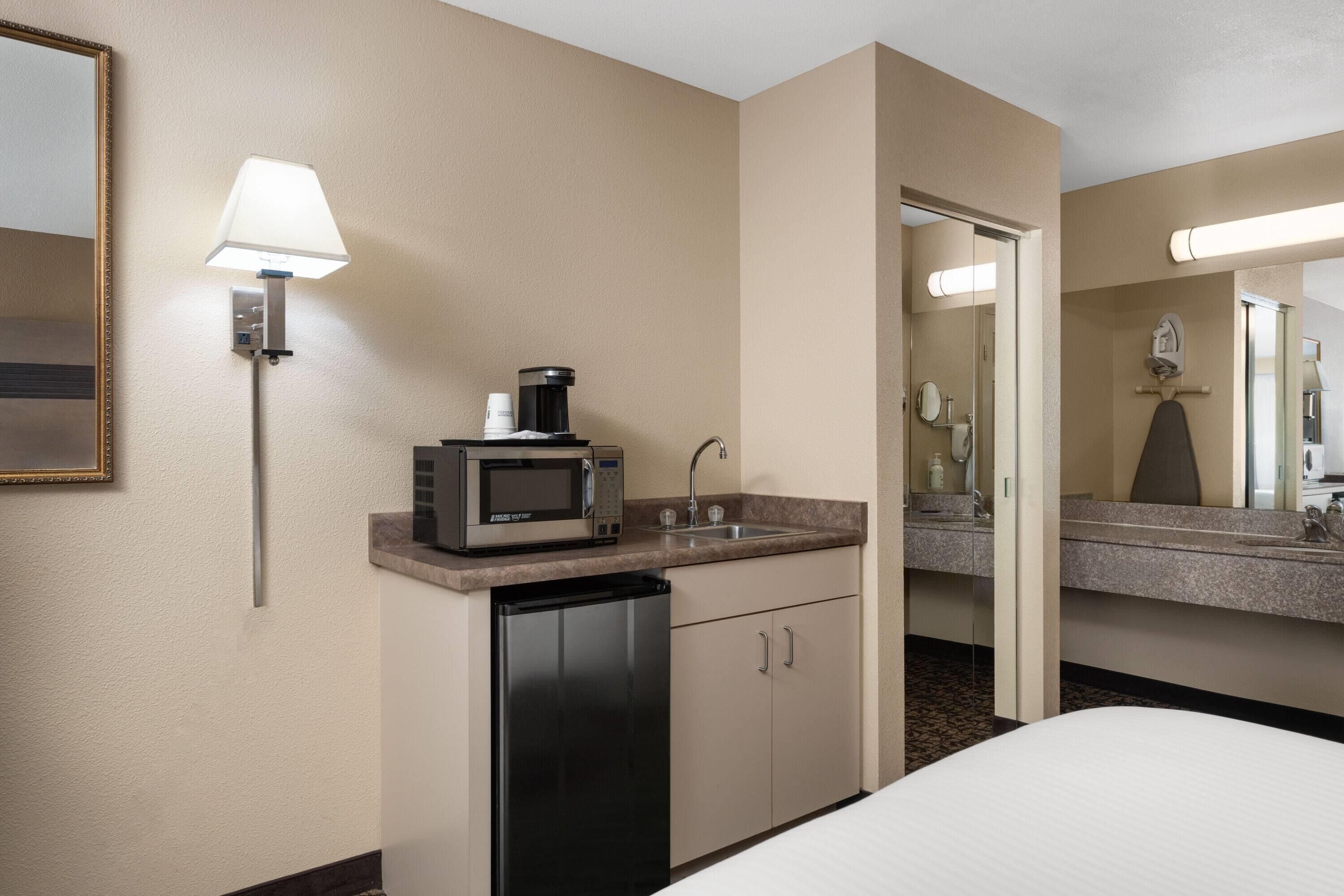 Habitación de hotel con kitchenette, que incluye microondas, cafetera y lavabo.