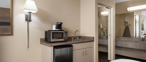 Habitación de hotel con kitchenette, que incluye microondas, cafetera y lavabo.