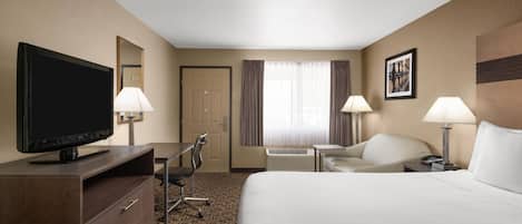 A hotel room with a bed, a desk, a television, a chair, and a window with curtains.