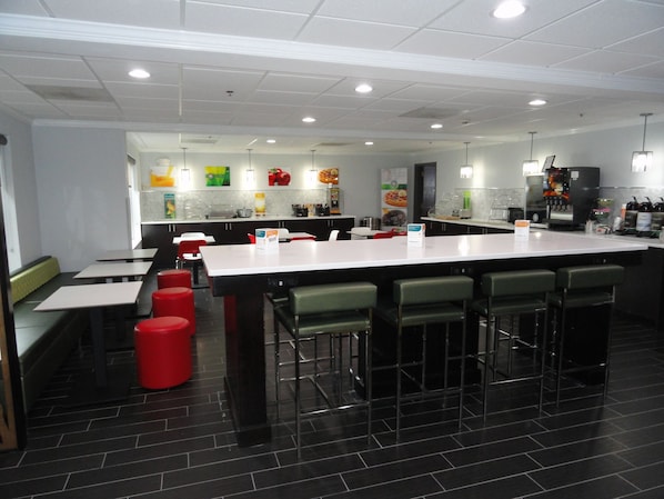 A modern restaurant with a long counter, bar stools, and red stools.