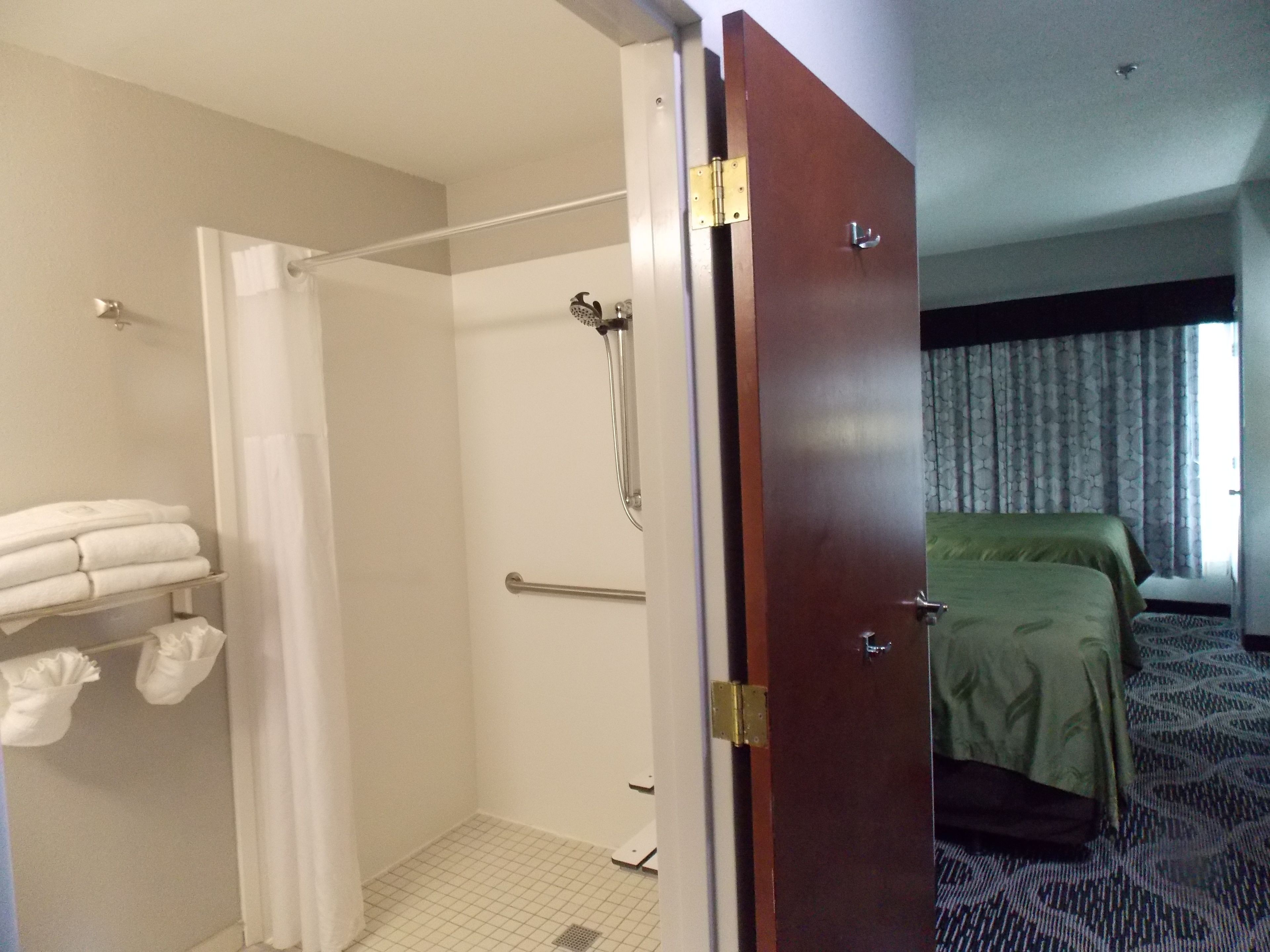 A hotel room with a shower, a bed, and a bathroom with towels.