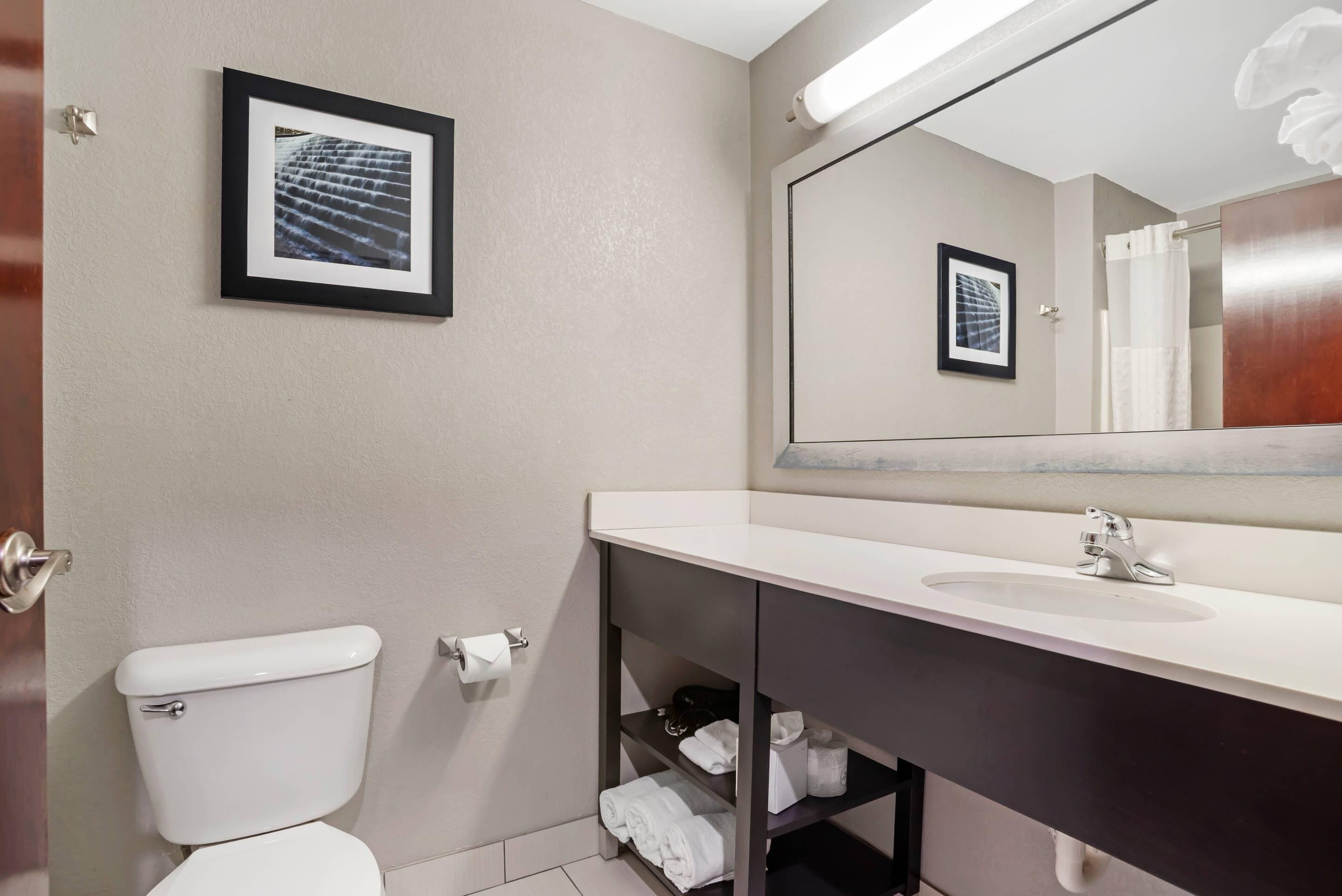 Een moderne badkamer met toilet, wastafel en een plank met handdoeken.