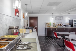 A modern kitchen with a buffet setup, including various food containers and a coffee machine.