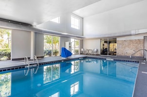 A swimming pool with clear blue water, surrounded by windows and a covered area.