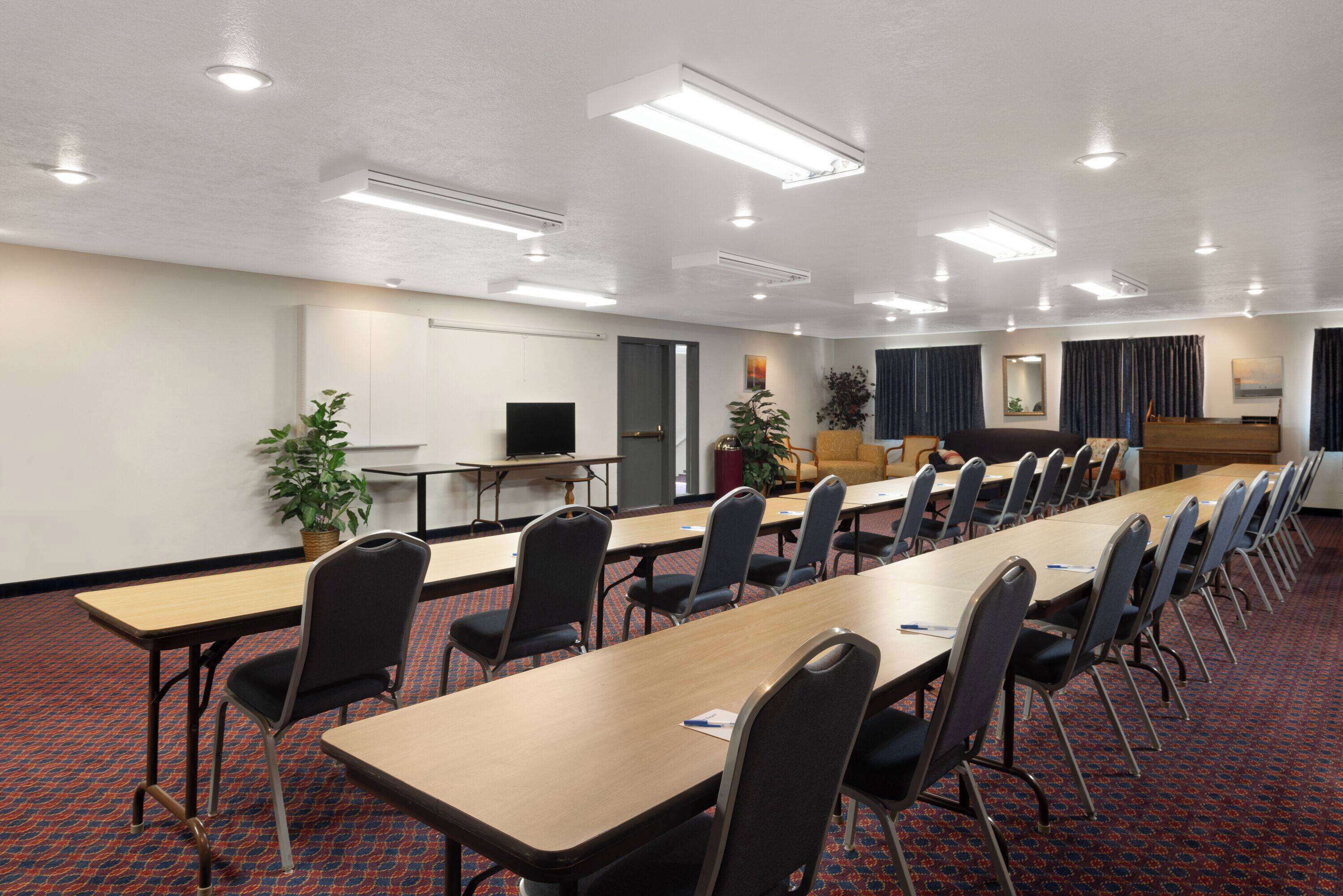 A conference room with long tables, chairs, and a television on a stand.