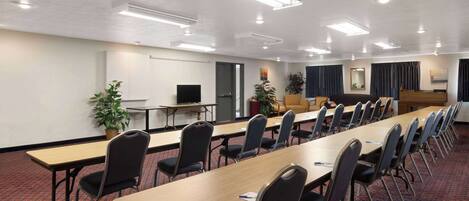A conference room with long tables, chairs, and a television on a stand.