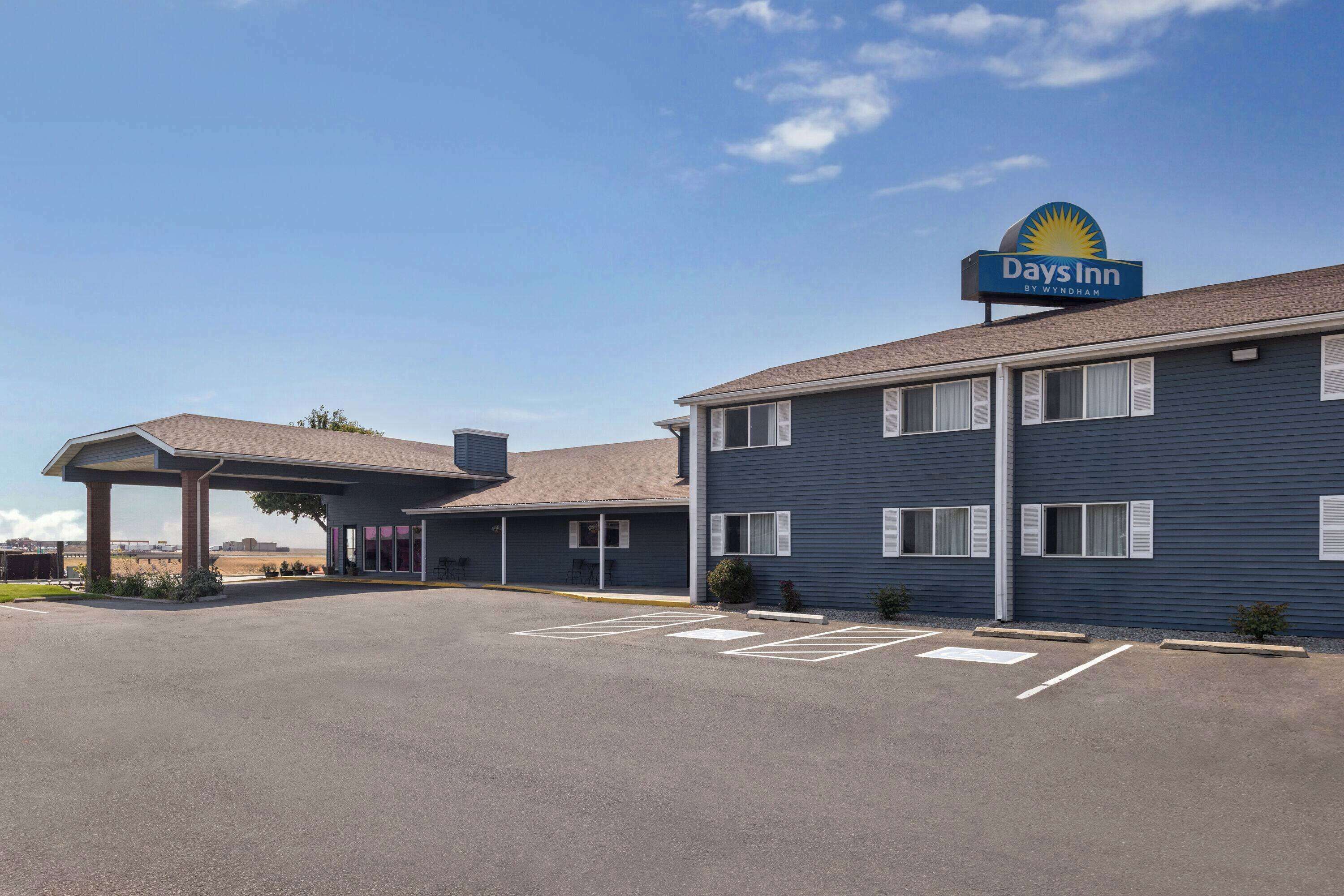 Een Days Inn by Wyndham met een overdekte parkeerplaats en een heldere lucht.