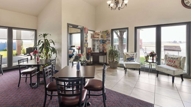 A spacious room with a dining area, a chandelier, and large windows offering a view.