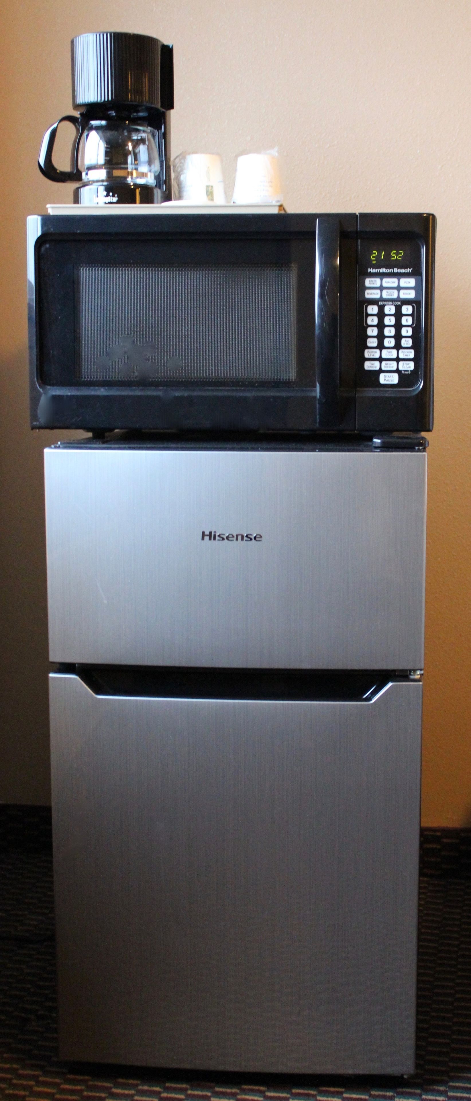 A stainless steel refrigerator with a digital microwave on top.