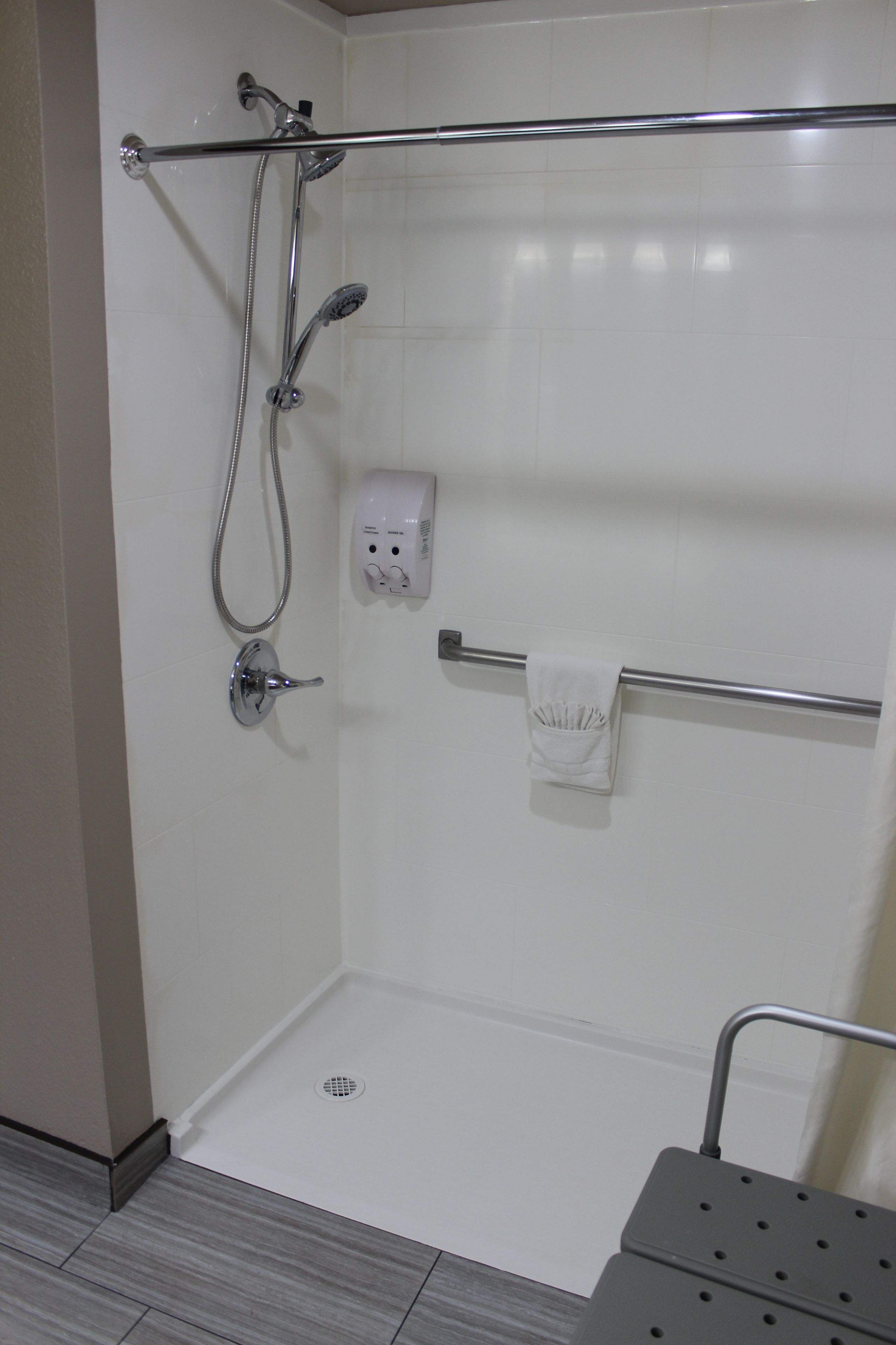 A shower area with a glass door, a towel rack, and a handheld showerhead.