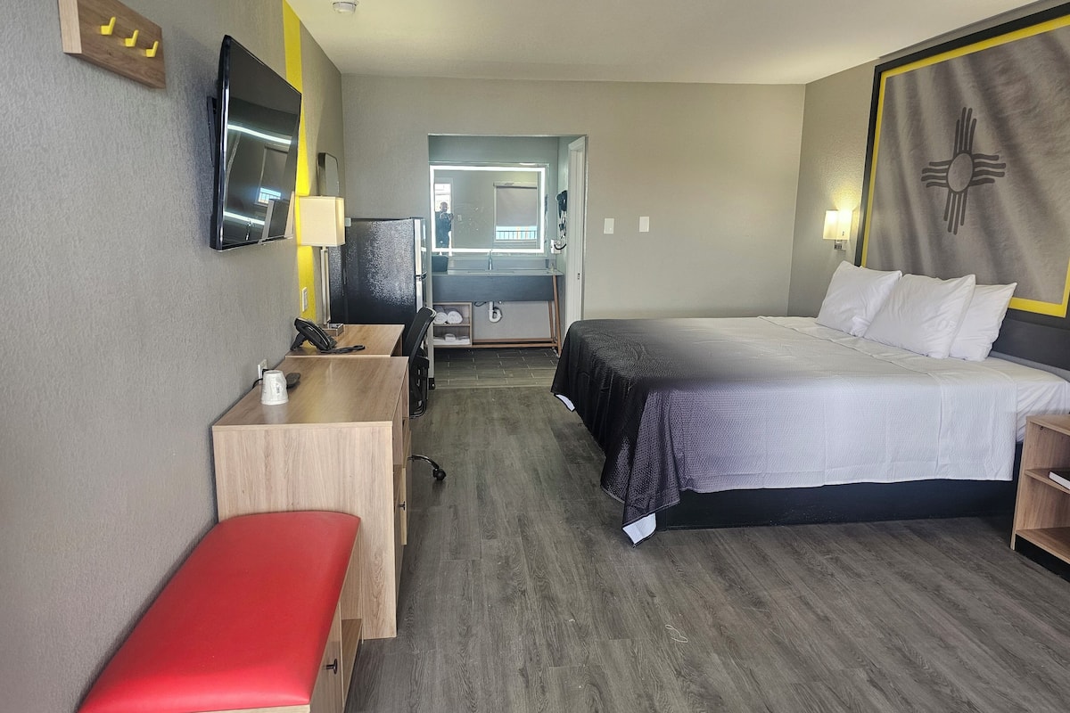 Een hotelkamer met een bed, bureau, stoel en een klein bankje.