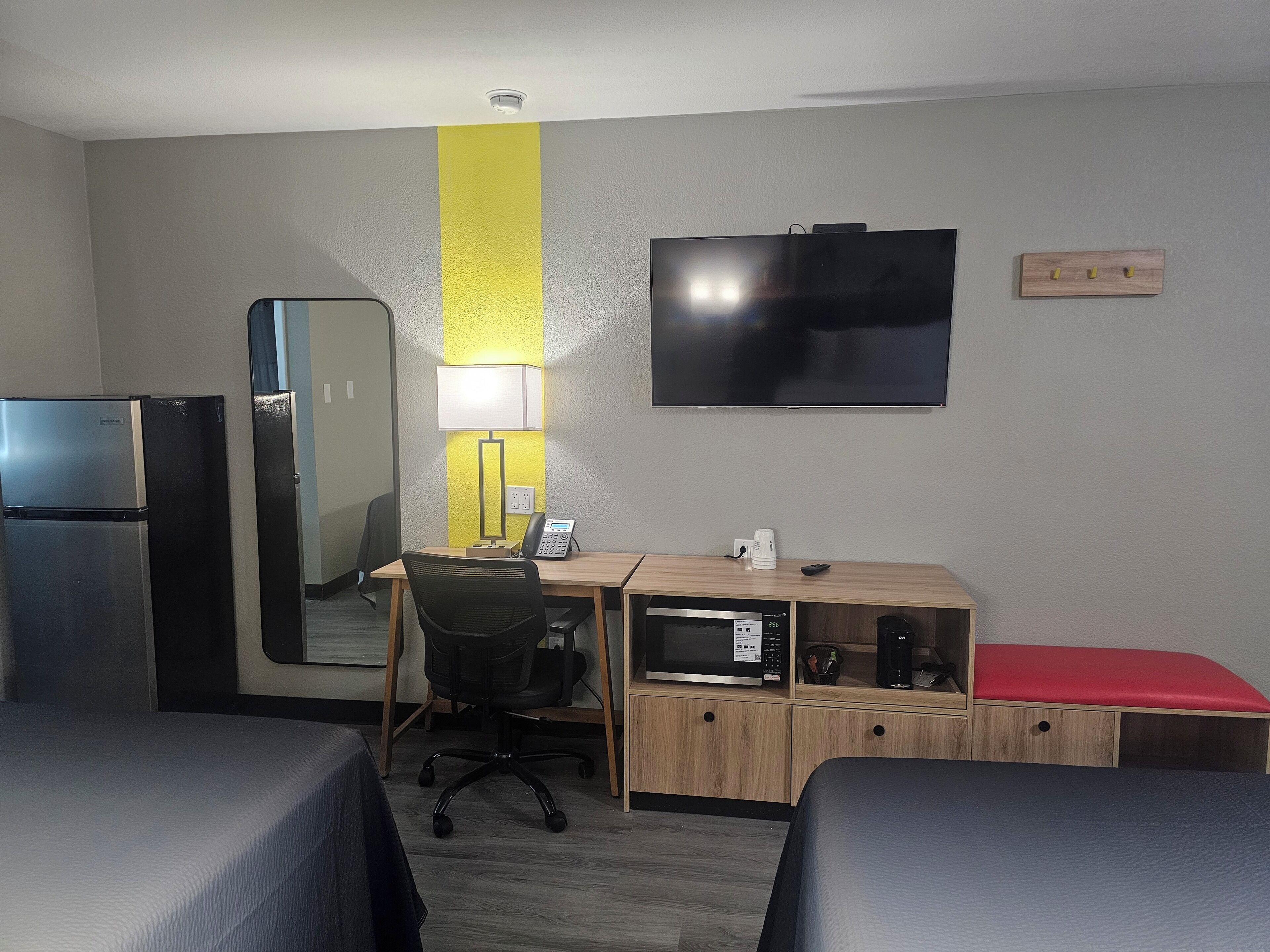 Une chambre d’hôtel comprenant un lit, un bureau avec une chaise, un four à micro-ondes, un réfrigérateur, une télévision et une table de chevet.
