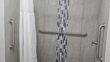 Área de chuveiro com piso ladrilhado, design de mosaico vertical em azulejos e cortina de chuveiro branca.