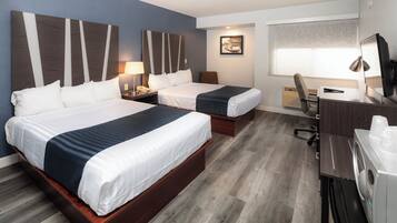 Habitación de hotel con dos camas, un escritorio con computadora, una silla, televisión y lavadora.
