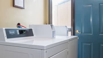 Un espace buanderie comprenant un lave-linge, un étendoir et une porte bleue.