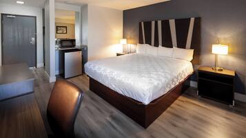 A modern hotel room with a large bed, a desk, and a microwave in the corner.