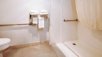 A bathroom with a toilet, a shower, and a towel rack with folded towels.