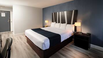 Une chambre d’hôtel moderne avec un grand lit, deux tables de chevet et une petite table d’appoint.