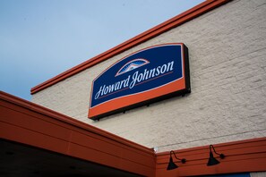 A sign for Howard Johnson on a building with a brick facade and orange trim.