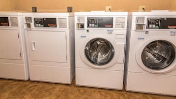 A row of white commercial dryers with digital displays and operating instructions.