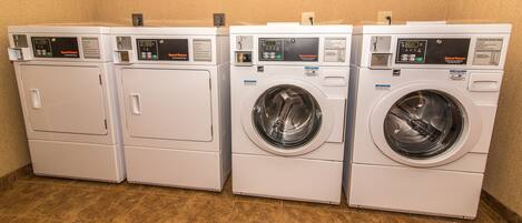 A row of white commercial dryers with digital displays and operating instructions.