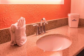 A bathroom sink with a towel rack and a trash bin.